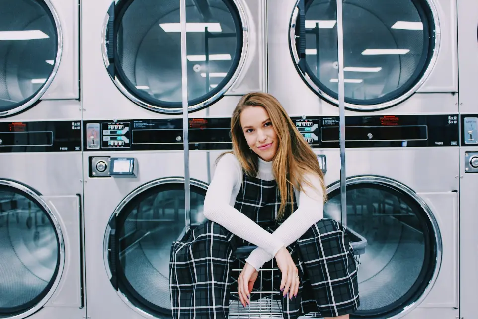 woman sitting on metal in front of laundry machines